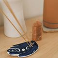 Incense sticks on a blue ceramic dish with a wooden surface and blurred background