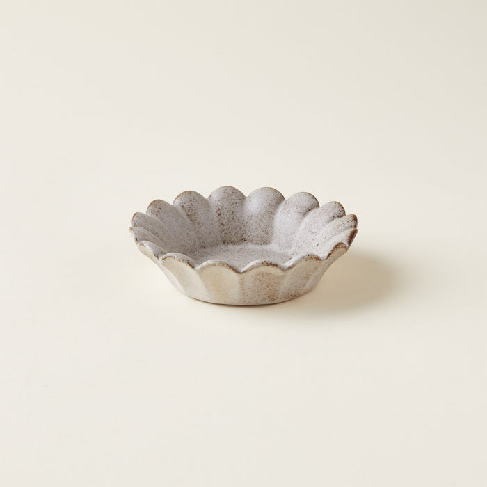 A small, decorative pinch bowl with a unique scalloped, petal-like shape.