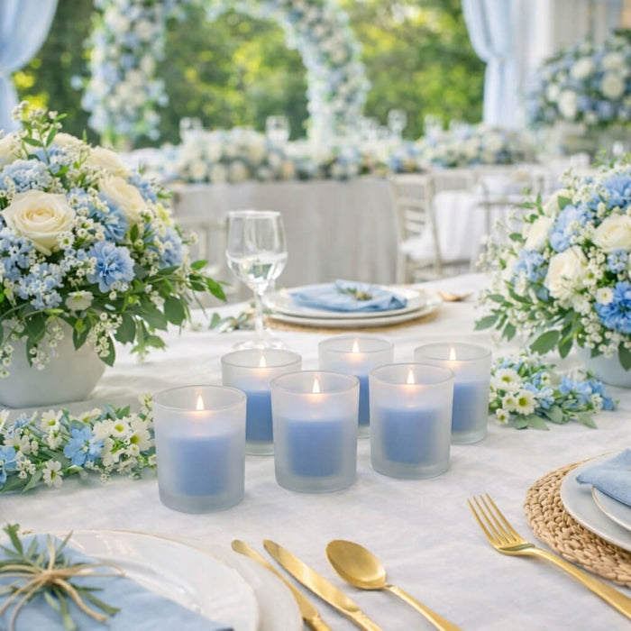 Six blue candles in Frosted Votive Holders on a wedding table setup with flowers