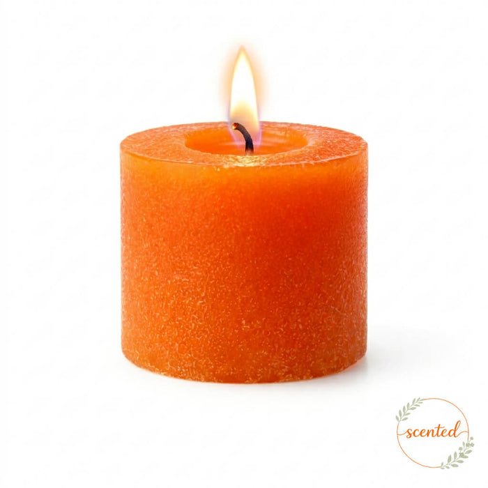 A single lit orange citrus scented votive candle