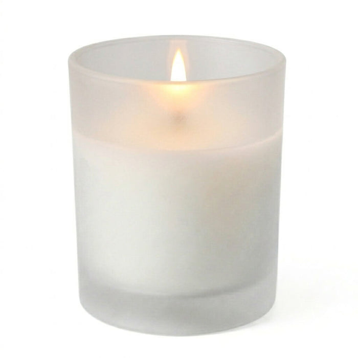 A lit white unscented candle in a frosted votive holder isolated on a solid white background