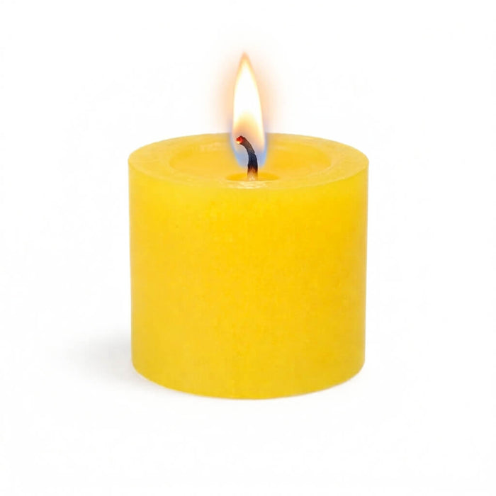 A single, lit yellow votive candle isolated on a solid white background