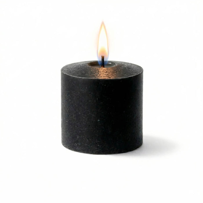 Lit unscented black votive candle on a white backdrop