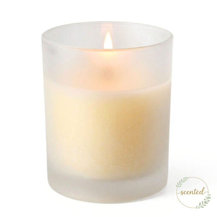 A lit vanilla scented candle glowing softly inside Frosted Votive Holders against white