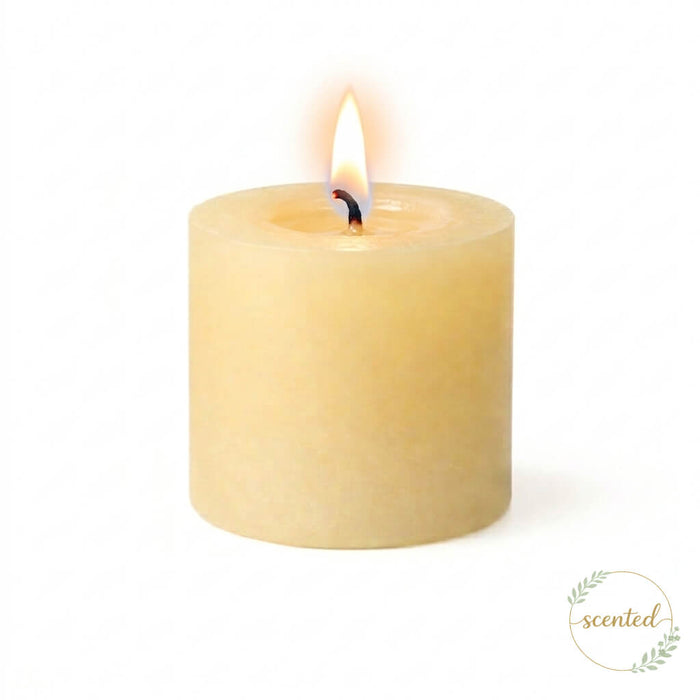 A scented lit ivory pillar candle on a white background