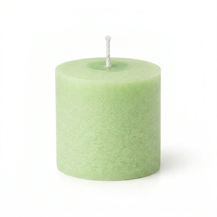 Close-up of an unlit green votive candle with a cotton wick
