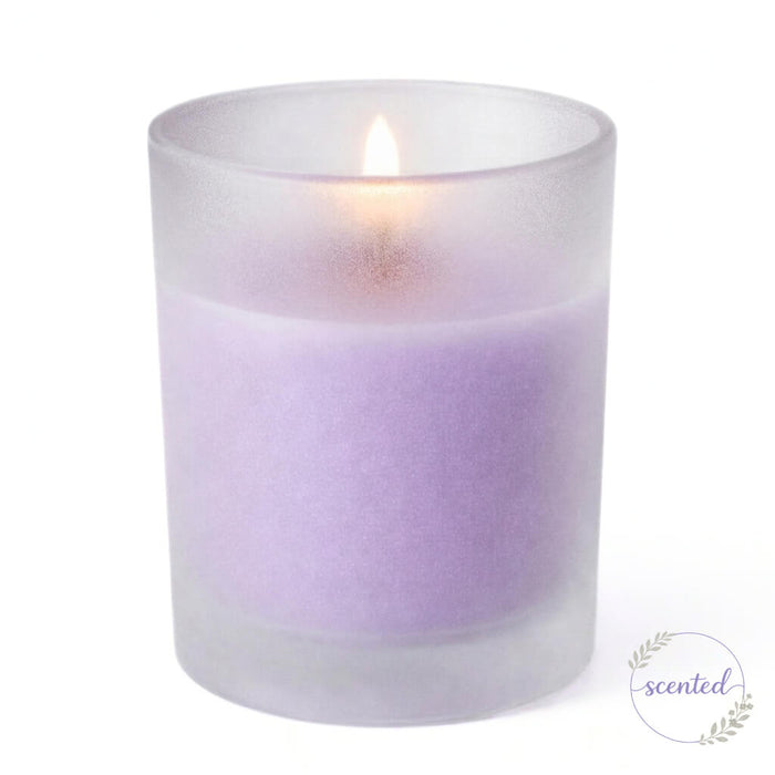 A lit lavender scented candle glowing softly inside Frosted Votive Holders against white