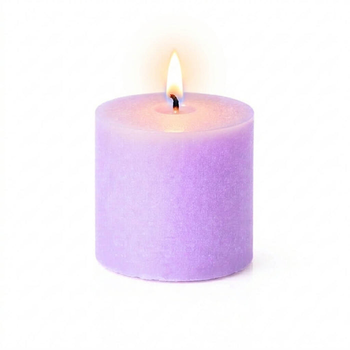 Close-up of a lit lavender candle on a white backdrop showing a warm flame