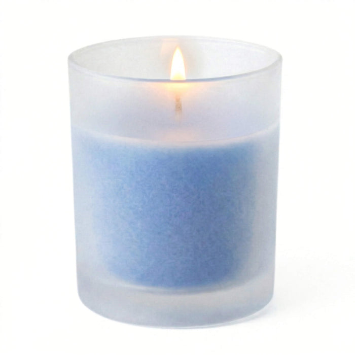 A lit blue candle inside one of the Frosted Votive Holders on white background