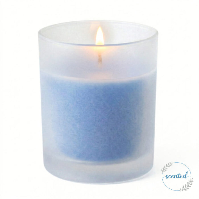 A scented light blue candle glowing inside Frosted Votive Holder against white