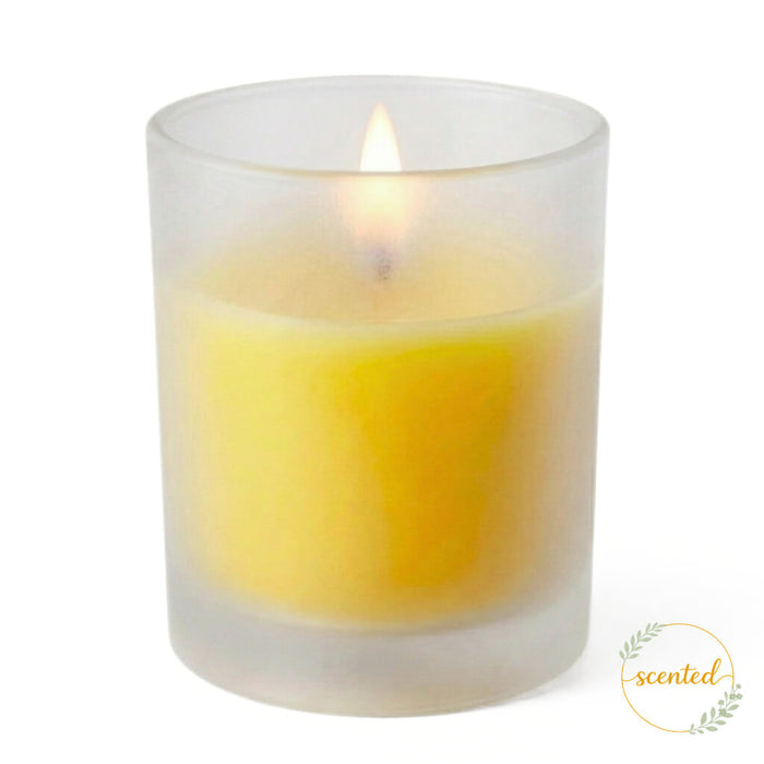 A lit Yellow - Lemon Meringue Scented candle in a frosted holder with a scented logo sticker