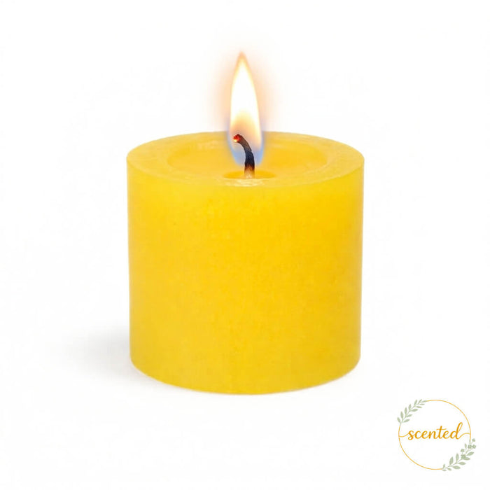 A lit yellow lemon meringue scented candle on a white background with a scented logo sticker