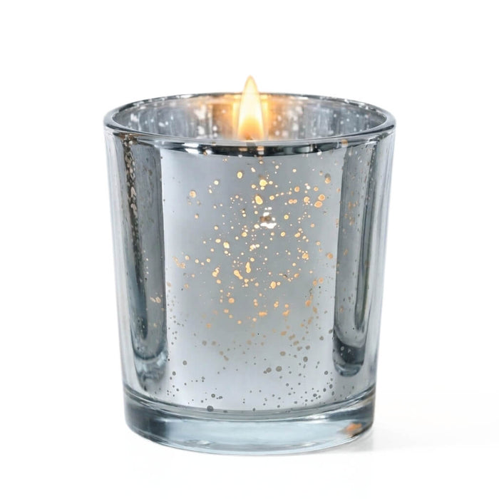 A single lit candle burning inside a Metallic Silver Mercury Votive Holder on a white surface